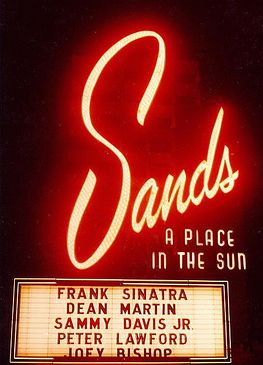 The iconic, glowing neon marquee of the Sands Hotel and Casino in Las Vegas during the 1960s.